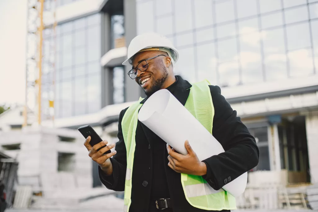 draughtsman in South Africa, young black race man with blueprint standing near glass building